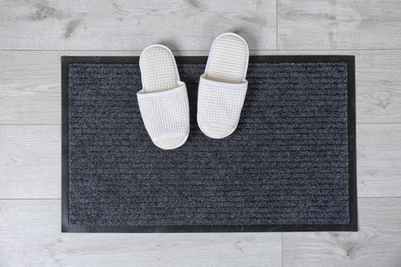 Door mat and slippers on floor, top view. Space for textの写真素材