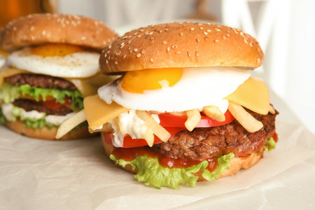 Tasty burgers with fried egg on parchmentの写真素材
