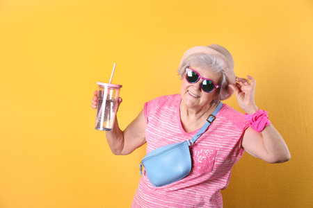 Portrait of cool grandmother with drink on color background, space for textの写真素材