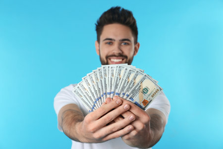 Happy young man with money on color backgroundの写真素材