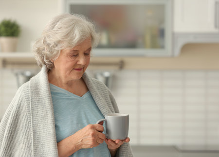 Elderly woman with cup of tea in kitchen. Space for textの写真素材