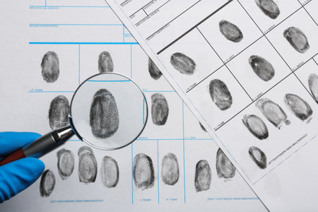 Criminalist studying fingerprints with magnifying glass, top viewの写真素材