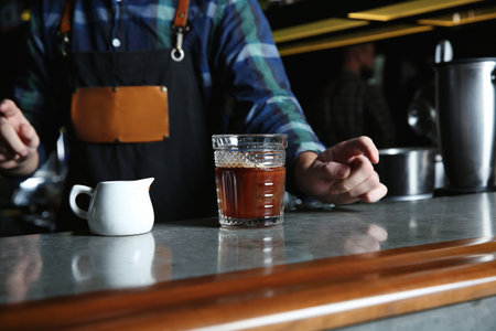 Barman with White Russian cocktail at counter in pub, closeup. Space for text