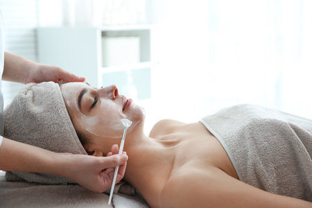 Cosmetologist applying mask on client's face in spa salonの写真素材