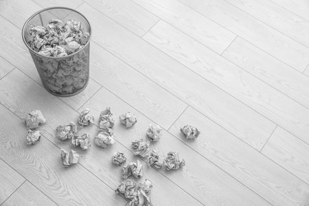 Metal bin and crumpled paper on floor, above view. Space for textの写真素材