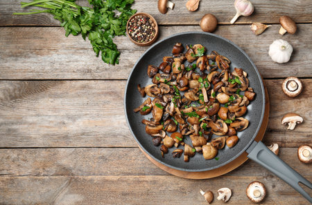 Frying pan of mushrooms on wooden background, flat lay with space for textの写真素材
