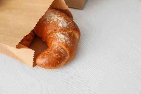 Paper bag with pastry on light wooden background. Space for textの写真素材