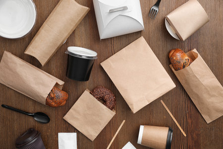 Flat lay composition with paper bags and different takeaway items on wooden background. space for designの写真素材