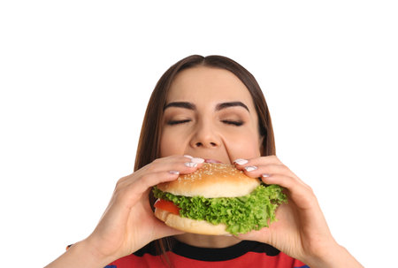 Young woman eating tasty burger on white backgroundの写真素材