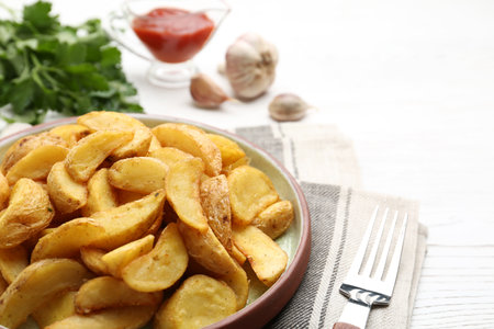 Plate with tasty baked potato wedges on wooden table, closeup. Space for textの写真素材