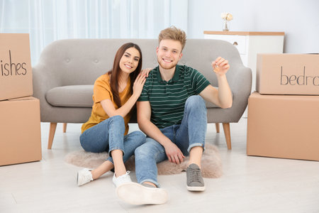 Young couple with key from their new house indoors. Moving day
