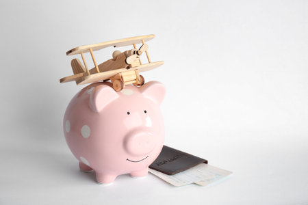 Piggy bank with toy airplane, passport and tickets on white background, space for text. travel agencyの写真素材