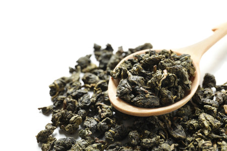 Tie Guan Yin oolong tea leaves and spoon on white background, closeup