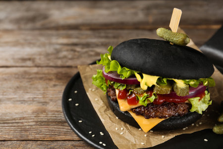 Slate plate with black burger on table, closeup. Space for textの写真素材