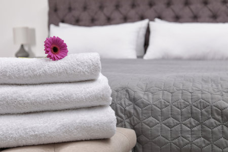 Stack of fresh towels on bedside bench in hotel roomの写真素材