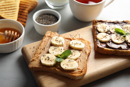 Tasty toasts with banana, mint and chia seeds on wooden boardの写真素材