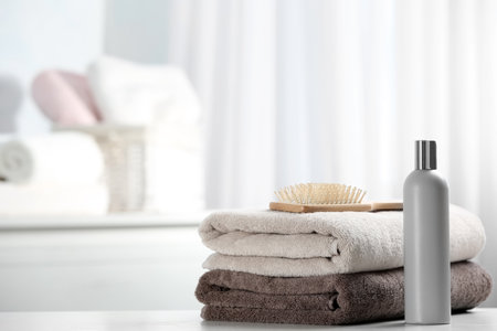 Towels with hair brush and shampoo on table. Space for textの写真素材