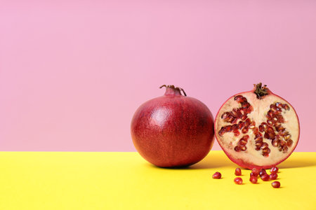 Delicious red ripe pomegranates on table against color background, space for textの写真素材