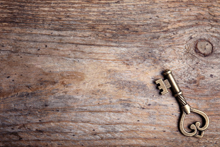 Old vintage key on wooden background, top view with space for textの写真素材