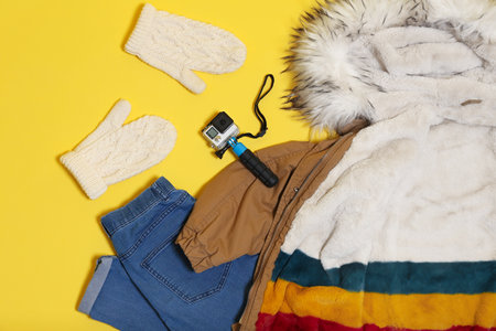 Set of warm clothes and action camera on color background, flat lay. winter holidaysの写真素材