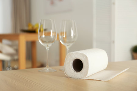 Roll of paper towels and glasses on table indoors. Space for textの写真素材