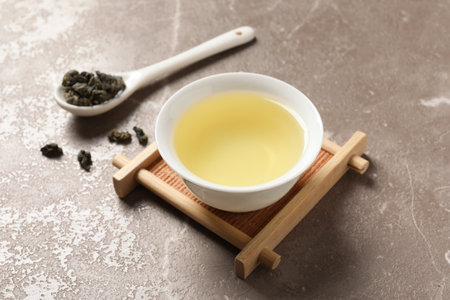 Cup of Tie Guan Yin oolong and spoon with tea leaves on tableの写真素材