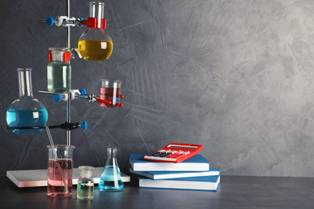 Laboratory glassware and school supplies on table against gray background, space for textの写真素材