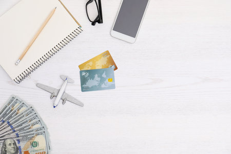 Flat lay composition with credit cards and plane model on wooden table in travel agencyの写真素材