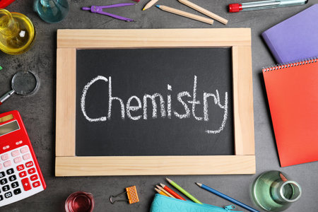 Laboratory glassware, school supplies and board with word CHEMISTRY on gray background, flat layの写真素材