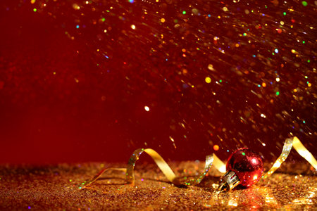 Golden glitter, Christmas ball and streamer against color background. Space for textの写真素材