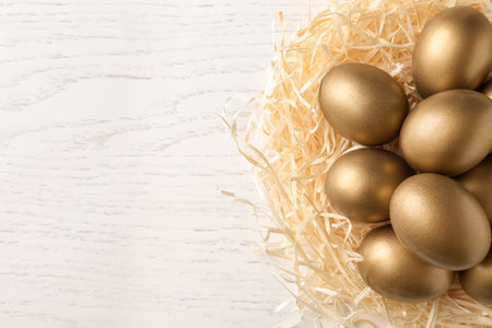 Golden eggs in nest on wooden background, top view with space for textの写真素材