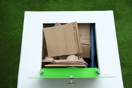 Trash bin with cardboard on color background, closeup. Recycling conceptの写真素材
