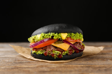Tasty black burger on table against dark backgroundの写真素材
