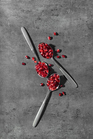 Flat lay composition with spoons and pomegranate seeds on gray backgroundの写真素材
