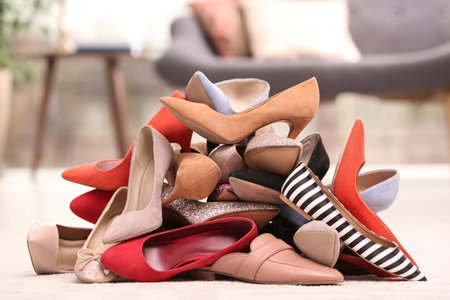 Heap of different shoes on floor in roomの写真素材