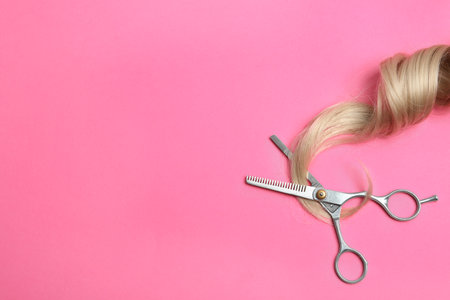 Hair lock and scissors on color background, top view with space for textの写真素材