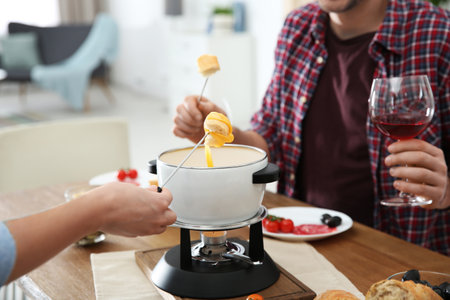 Couple having fondue dinner at table indoors, closeupの写真素材