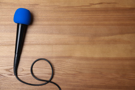 Modern microphone on wooden background, top view with space for textの写真素材