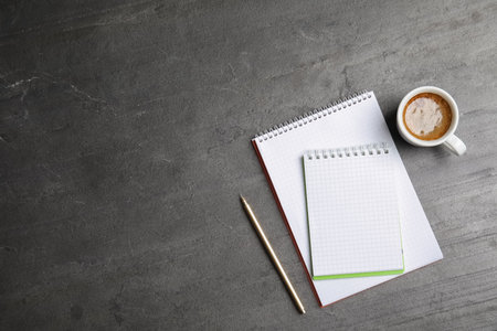Notebooks and coffee on gray background, top view with space for textの写真素材