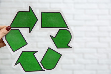 Woman holding paper recycling symbol on light background, closeup. Space for textの写真素材