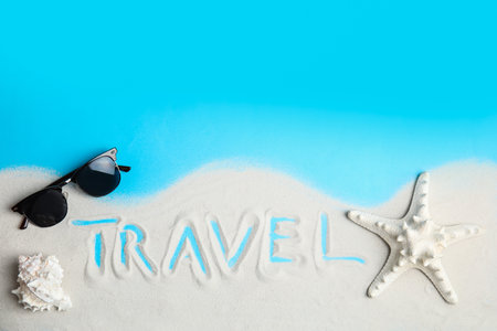 Flat lay composition with sand, sunglasses and word TRAVEL on color background, space for text. tourist agencyの写真素材