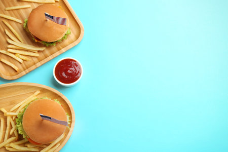 Tasty burgers, French fries and sauce on color background, top view with space for text. traditional american foodの写真素材