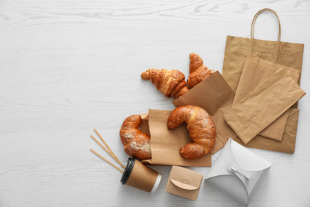 Flat lay composition with paper bags and pastry on light wooden background. space for designの写真素材