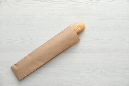 Baguette in paper bag on wooden table, top view with space for textの写真素材