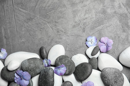 Zen stones and exotic flowers on gray background, top view with space for textの写真素材