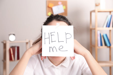 Young woman with note HELP ME on forehead indoorsの写真素材