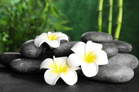 Zen stones and exotic flowers on table against blurred backgroundの写真素材