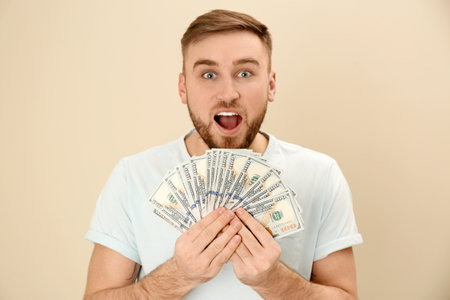 Portrait of emotional young man with money on color backgroundの写真素材