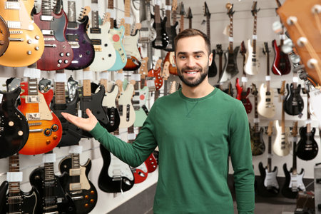 Young shop assistant near guitars in music storeの写真素材