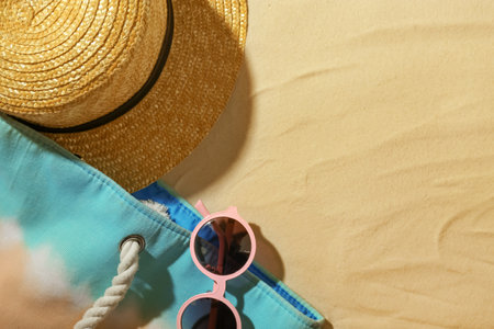 Beach accessories on sand, top view. Space for text